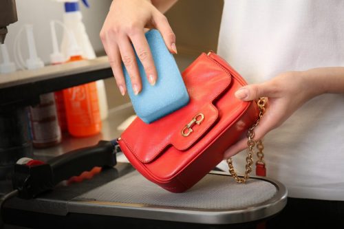 Dry cleaning business concept. Woman washing bag with sponge