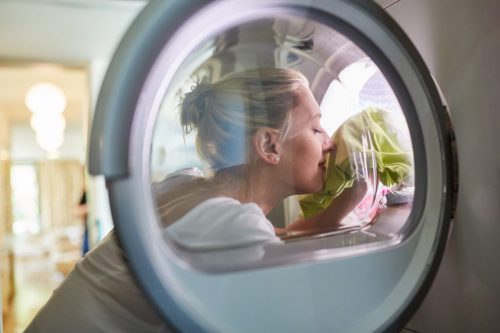Hausfrau mit frischer Wäsche in der Waschmaschine